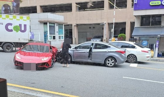 회색 아반떼 차량이 빨간색 람보르기니 우라칸 차량을 옆에서 들이받은 채 멈춰 있다. 아반떼 차주가 차에서 내려 놀라는 모습. 사진 온라인 커뮤니티 캡처