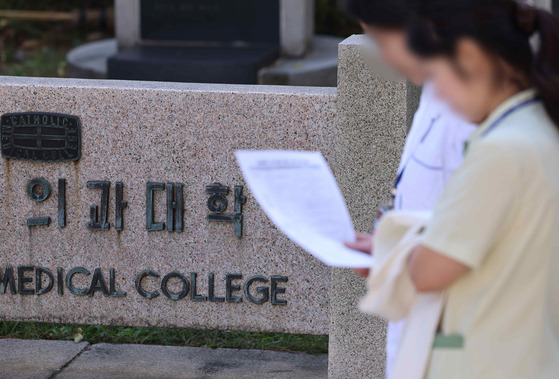 People pass by a medical school in downtown Seoul on Wednesday. [YONHAP]