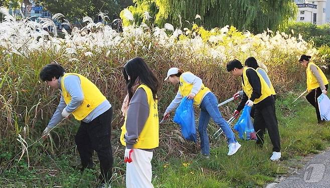 한국장학재단 전북지역센터와 전국대학교장학·학자금융자협의회 회원들이 전주천 주변에서 환경정화 활동을 실시했다.(우석대 제공)/뉴스1