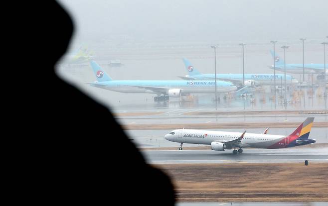 인천국제공항 계류장에 세워진 대한항공 항공기 앞으로 아시아나 항공기가 이륙하고 있다. /뉴스1