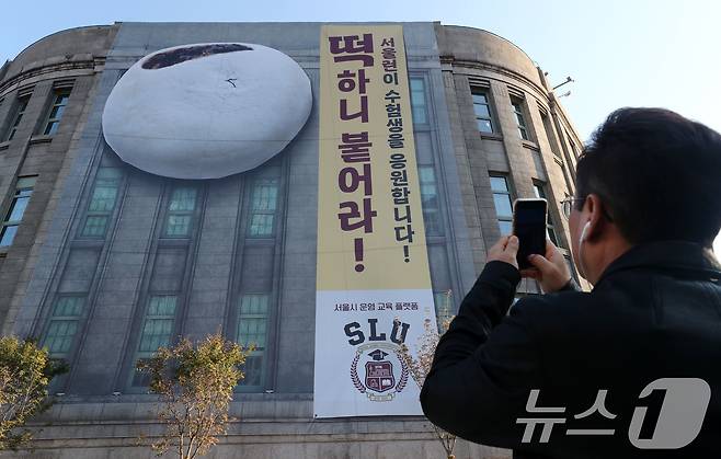 한 시민이 서울도서관 외벽에 걸린 수험생을 응원하는 대형 현수막 사진을 찍고 있다. /뉴스1 ⓒ News1 박세연 기자