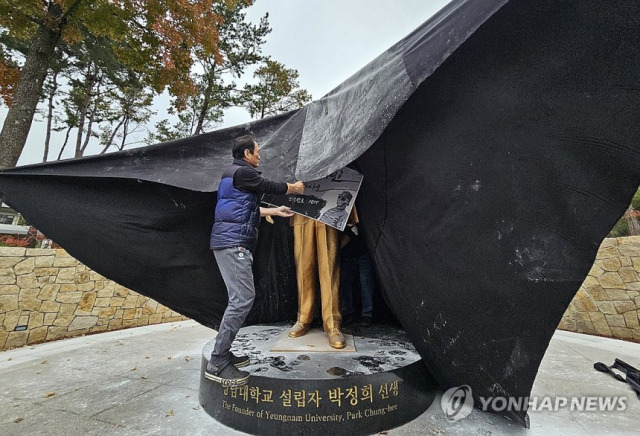 ▲ 10일 오후 경북 경산시 영남대학교에서 영남대 민주동문회원들이 대학 내 설치된 박정희 동상에 검은 천을 두르고 있다. ⓒ 연합뉴스