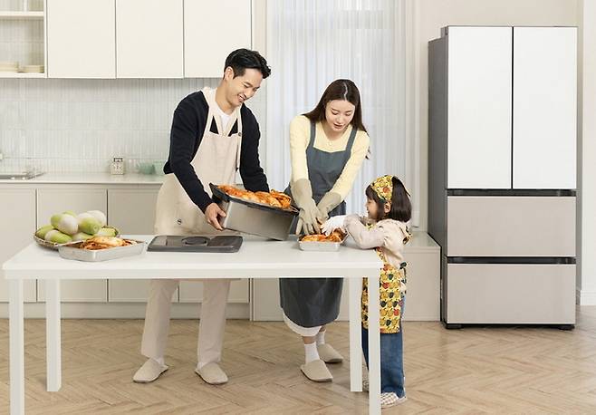 삼성전자 모델들이 김치 냄새 퍼짐을 줄여주는 ‘냄새 케어 김치통’에 김장 김치를 담아 ‘비스포크 AI 김치플러스’에 보관하고 있다. 삼성전자 제공