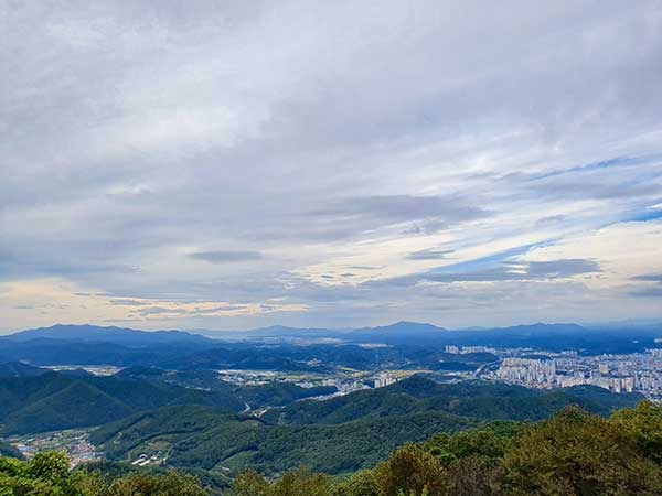 정상에서 내려다본 멀리 남해의 산들, 오른쪽 진주시가지.