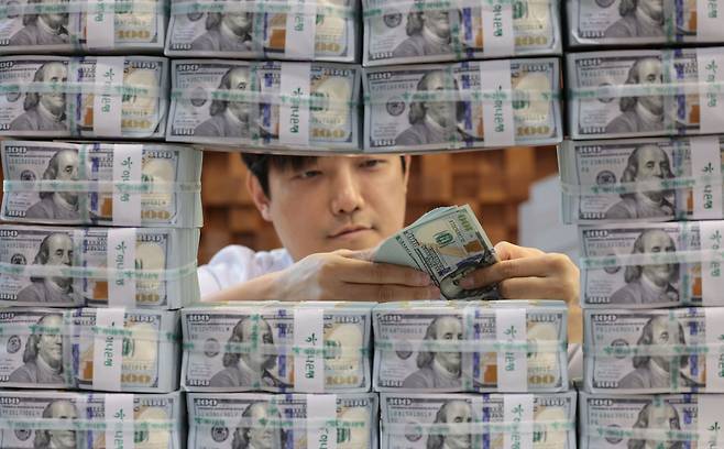 A banker checks US dollar bills at KEB Hana Bank in Seoul on Thursday. (Yonhap)