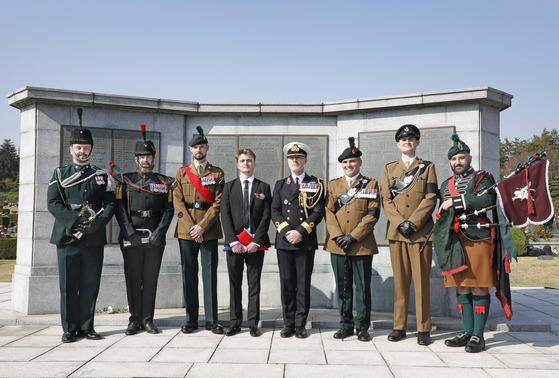 Cpt. William Adair's great-grand-nephew Cameron Adair, fourth from left, stands next to Brig. Gen. Andy Lamb, fourth from right, in front of the cenotaph at the United Nations Memorial Cemetery in Busan on Tuesday. They are flanked by members of the Royal Irish Regiment and the Gloucestershire Regiment. [PARK SANG-MOON]