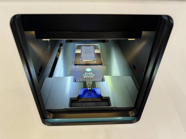 민팃ATM 수납함에 민팃 커넥트 앱을 실행한 채 휴대폰을 넣으면 AI로 자동으로 진단하고 판매금액을 책정한다.