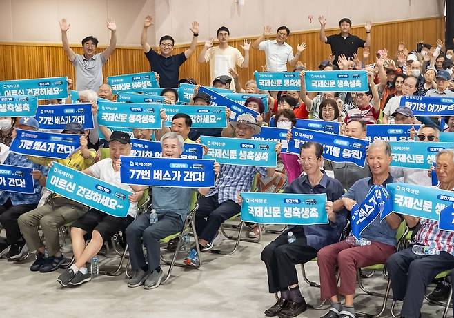 8월30일 부산 연제구 부산시종합복지관에서 국제신문 창간 77주년을 맞아 '어르신과 함께 하는 국제신문 생일잔치' 행사가 열렸다. 플래카드를 든 어르신들 뒤편에 선 복지관 관계자와 '77번 버스팀' 박호걸, 신심범 기자(왼쪽에서 두 번째와 세번째), 김진룡 기자(다섯번째)가 손을 흔들고 있다. /국제신문 제공