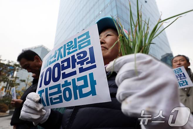 20일 오후 서울 중구 농협중앙회 본점 인근에서 열린 전국마늘양파생산자대표자대회에서 양파 모종을 든 참가자들이 재난지원금 지급 등을 촉구하고 있다. 2024.11.20/뉴스1 ⓒ News1 이동해 기자