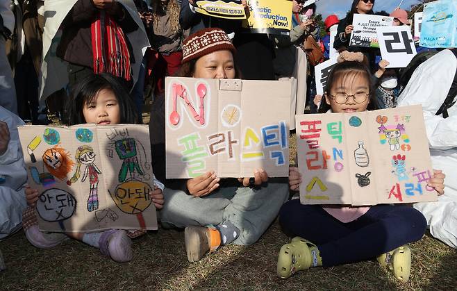 유엔 플라스틱 협약 제5차 정부 간 협상위원회 회의를 이틀 앞둔 23일 오후 부산 해운대구 올림픽공원 일대에서 열린 ‘1123 부산 플라스틱 행진’ 참가자들이 손팻말을 들고 있다. 김혜윤 기자