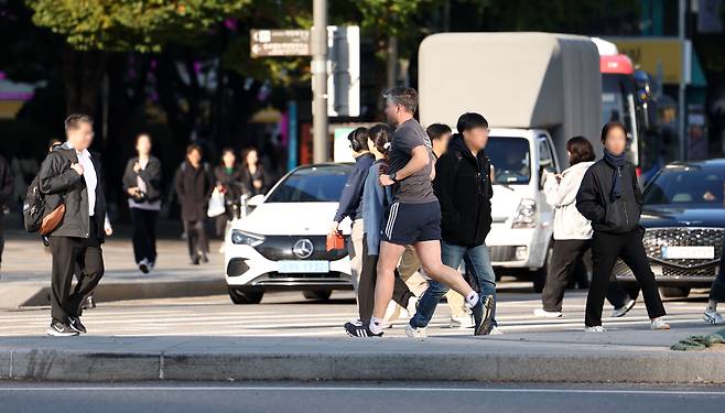 올 가을 최저 기온을 기록한 지난달 24일 오전 서울 종로구 세종대로 사거리에서 반팔·반바지 차림의 한 외국인이 운동을 하고 있다. /뉴시스