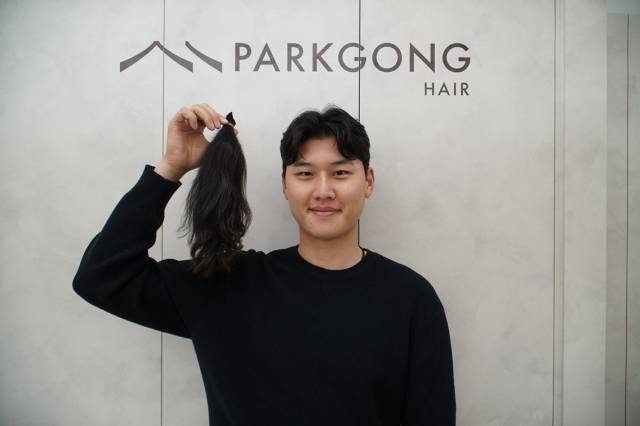 3년간 길러온 머리카락을 잘라 소아암 환우 가발 제작을 위해 기부한 이유석이 머리카락을 들어 보이며 환하게 웃고 있다. KPGA