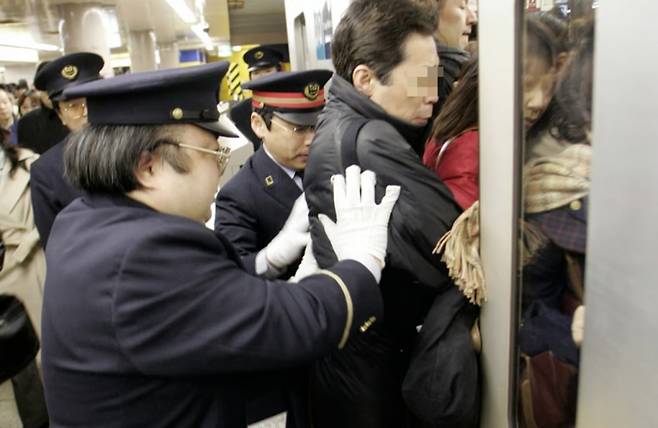 역무원들이 출퇴근 시간, 사람들을 지하철에 밀어넣고 있다. /사진=로이터
