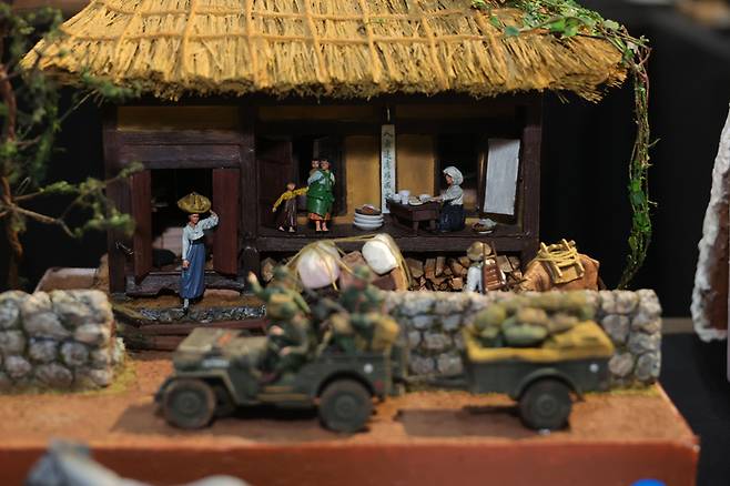 스미스부대장과 피난을 준비하는 가족들 6.25 전쟁 중 스미스부대가 북한군의 남침을 저지하기 위해 이동 중 피난민을 만나는 모습을 작가의 상상력으로 재현. 보금자리를 떠나 피난을 가야 하는 피난민들의 안타까움이 느껴지는 듯하다.