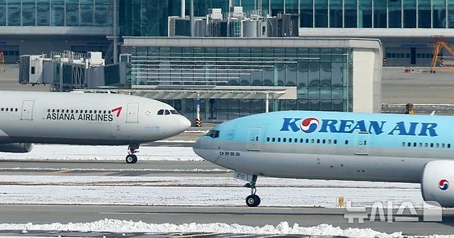 [인천공항=뉴시스] 김선웅 기자 = 대한항공이 아시아나항공과의 기업결합을 위해 유럽연합(EU) 경쟁당국이 제시한 조건부 승인의 선행 조건을 모두 충족하며 28일 사실상 인수 작업 마무리 수순에 들어갔다.  미국 법무부(DOJ)의 심사가 남았지만 양사 합병에 대해 독과점 소송을 제기하지 않는다면 승인으로 간주한다. 대한항공은 미국 DOJ에 EU 경쟁당국의 최종 승인 내용을 보고한 상태다. 지난 2021년 1월 기업결합을 위해 나선 지 약 4년 만이다. 29일 인천국제공항 활주로에서 대한항공·아시아나항공 양사 항공기가 오가고 있다. 2024.11.29. mangusta@newsis.com