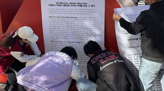 [대구=뉴시스] 3일 대구 경북대학교 북문 앞에서 민주주의를 요구하는 경북대 대학생 모임이 '윤석열 대통령 퇴진'을 요구하는 기자회견을 마친 뒤 대자보에 연서명자 명단을 게시하고 있다.  *재판매 및 DB 금지