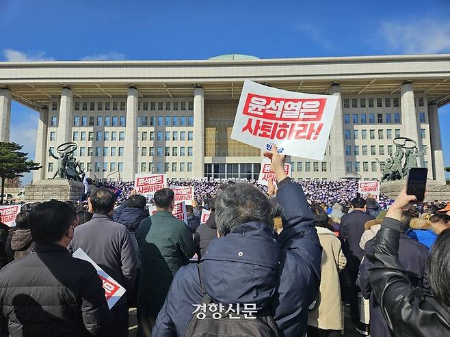 비상계엄령이 해제된 4일 한 시민이 서울 여의도 국회 본청 앞에서 ‘윤석열은 사퇴하라’라고 적힌 손팻말을 들고 있다. 김송이 기자