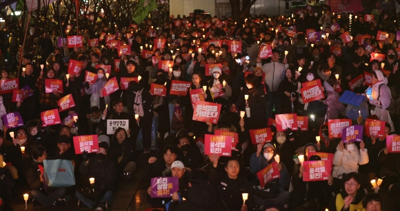 다시 촛불 든 시민들 - 비상계엄 사태 여파가 이어진 5일 서울 종로구 동화면세점 앞에서 시민단체 주최로 열린 ‘윤석열 대통령 퇴진 촉구’ 집회에서 시민들이 촛불을 들고 정권 퇴진을 요구하고 있다. 촛불집회를 마친 참가자들은 용산 대통령실 앞까지 행진했다. 뉴스1