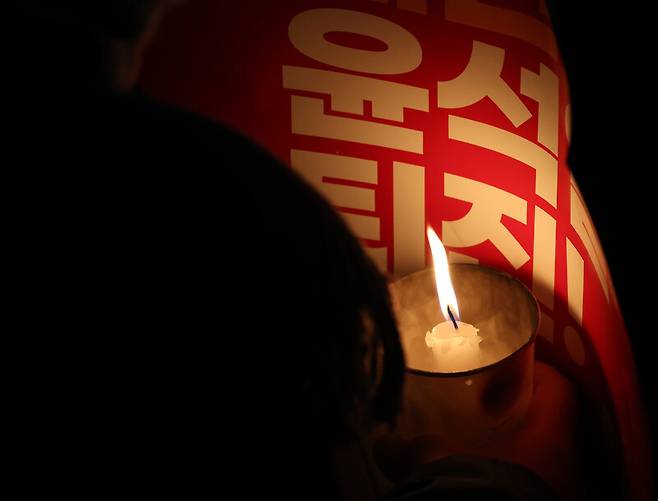 6일 저녁 서울 여의도 국회 앞에서 열린 ‘내란범 윤석열 퇴진 시민 촛불’ 집회에서 한 시민이 손팻말로 촛불을 지키고 있다. 김영원 기자 forever@hani.co.kr