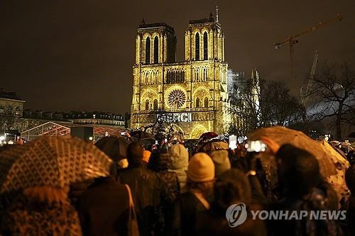 '감사합니다'  (파리 AP=연합뉴스) 7일(현지시간) 프랑스 파리에서 노트르담 대성당 재개관식을 보기 위해 인파가 몰린 가운데 성당 복원에 애써준 이들에 대한 감사의 메시지가 대성당 외부에 투영되고 있다. 2024.12.07 photo@yna.co.kr