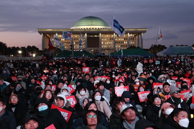 지난 7일 서울 여의도 국회 의사당 앞에서 시민들이 윤석열 대통령 탄핵안 투표 결과를 대형 화면으로 지켜보고 있다. 김봉규 선임기자 bong9@hani.co.kr