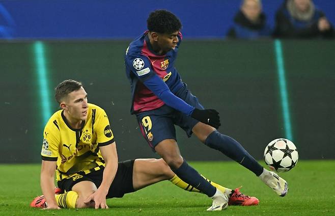 바르셀로나의 스페인 포워드 19번 라민 야말(오른쪽)과 보루시아 도르트문트의 독일 수비수 4번 니코 슐로터벡이 2024년 12월 11일 독일 서부 도르트문트에서 열린 보루시아 도르트문트와 FC 바르셀로나의 UEFA 챔피언스리그 축구 경기 중 공을 다투고 있다.