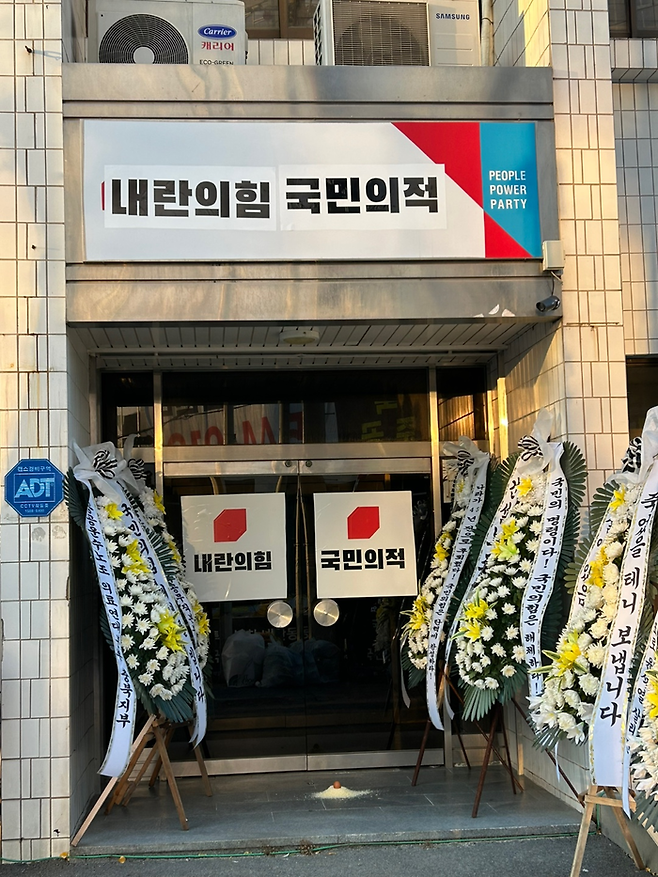 충북지역 시민단체들로 구성된 충북시국회의가 12일 오전 국민의힘 충북도당 간판과 입구에 ‘내란의힘’, ‘국민의적’이라고 쓰인 인쇄물을 붙였다. 충북시국회의 제공.