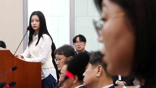 Hanni, a member of K-pop group NewJeans, looks at Kim Ju-young, Ador CEO and Hybe CHRO, during a National Assembly audit in Yeouido, Seoul, on Oct. 15. (Newsis)