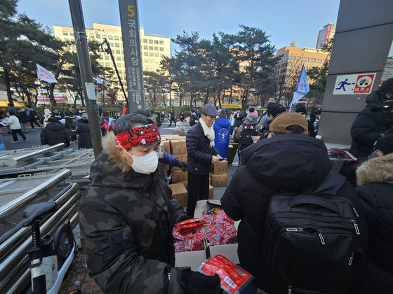 13일 국회의사당역 앞 시민들이 집회 참여자들에게 핫팩을 나눠주는 모습. 정세희기자