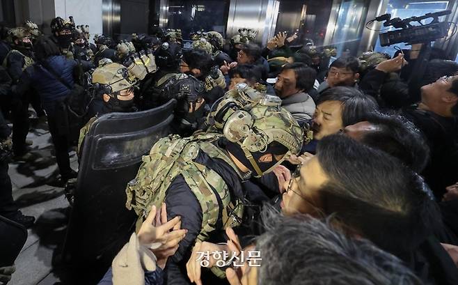 윤석열 대통령이 비상계엄을 선포한 후 자정을 넘긴 지난 4일 새벽 서울 여의도 국회의사당에 도착한 무장군인들이 국회본청 진입을 시도하자 국회 직원 등이 격렬히 막아서고 있다. 성동훈 기자