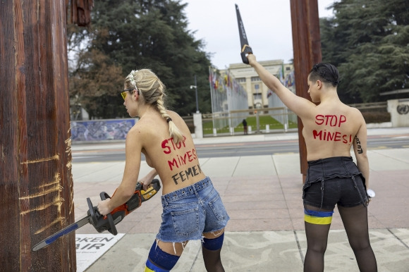 13일(현지시간) 페미니스트 단체 페멘(Femen) 활동가들이 스위스 제네바 유엔유럽본부 앞 광장의 ‘부서진 의자’ 기념비 아래에서 러시아의 유엔 추방을 요구하는 시위를 벌이고 있다. AP 연합뉴스