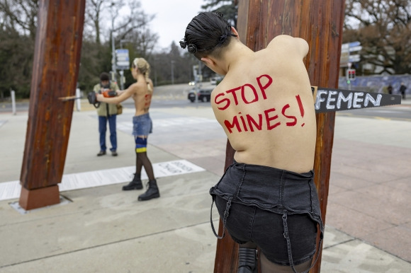 13일(현지시간) 페미니스트 단체 페멘(Femen) 활동가들이 스위스 제네바 유엔유럽본부 앞 광장의 ‘부서진 의자’ 기념비 아래에서 러시아의 유엔 추방을 요구하는 시위를 벌이고 있다. AP 연합뉴스