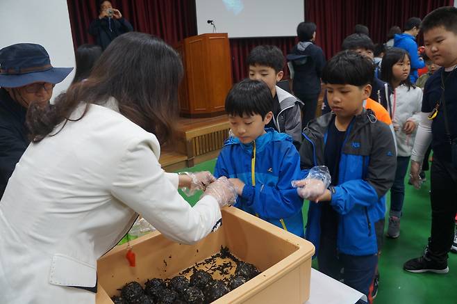 A teacher hands out rice balls to elementary school students on May 9, 2018, as part of a commemorative event for the Gwangju Uprising in 1980. [JOONGANG DB]