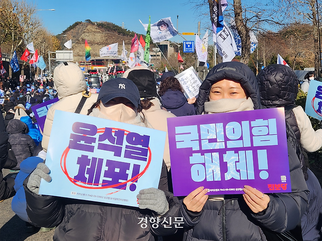 엄승원씨(32·오른쪽)와 동생 엄승윤씨(30)가 22일 오전 서울 남태령역 인근에버 벌어진 이른바 ‘남태령 대첩’에서 ‘윤석열 체포’와 ‘국민의 힘 해체’라고 쓴 손팻말을 들어 보이고 있다. 오동욱 기자