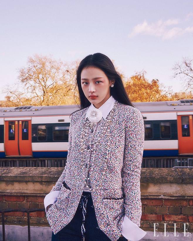 맑고 신선한 런던의 공기가 쿨한 민지를 에워싸던 순간. 레 베쥬 쿠션을 얼굴 전체적으로 얇고 고르게 바른 뒤 N°1 DE CHANEL 레드 까멜리아 립 앤 치크 밤, 2 헬시 핑크를 눈 밑부터 양볼까지 넓게 펴 발라 쌀쌀한 날씨에 살짝 상기된 듯한 치크 메이크업을 완성한다. 또렷함을 더하기 위해 스틸로 쑤르씰 오뜨 프레시지옹, 154 블롱 땅드르로 눈썹의 빈 곳을 메우듯 그려주고, 입술에 얇은 코팅 막을 형성해 눈부시게 빛나는 색감을 자랑하는 루쥬 코코 플래쉬, 90 쥬르를 바른다. 사용 제품은 모두 Chanel. 트위드 재킷과 데님 버뮤다 팬츠, 화이트 까멜리아 코르사주와 펄 네크리스, 이어링은 모두 Chanel.