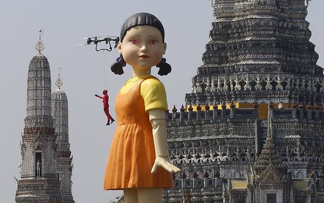 지난 21일(현지시각) 태국 방콕에서 열린 ‘오징어 게임 시즌2’ 홍보 행사에서 차오프라야강 위 바지선에 있는 대형 ‘영희’ 인형과 왓 아룬 사원이 보인다. 방콕/EPA 연합뉴스