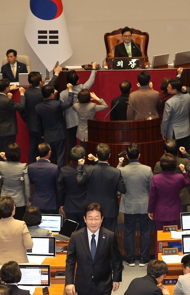 가결 요건에 항의하는 국민의힘, 자리로 향하는 이재명 대표 (서울=연합뉴스) 박동주 기자 = 우원식 국회의장이 27일 오후 국회 본회의에서 한덕수 국무총리 탄핵소추안 가결 요건을 '재적 과반'으로 정하자, 이에 대해 국민의힘 의원들이 항의하고 있다. 그 뒤로 투표를 마친 더불어민주당 이재명 대표가 자리로 향하고 있다. 2024.12.27 pdj6635@yna.co.kr (끝)