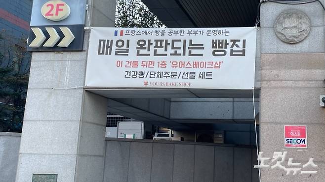 가게 홍보의 일환으로 큰 도로 쪽 주차장 입구에 붙인 현수막. 가게는 건물의 뒤편에 있다. 장규석 기자