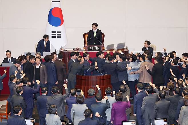 우원식 국회의장이 27일 오후 국회 본회의에서 한덕수 대통령 권한대행 겸 국무총리에 대한 탄핵소추안 표결과 관련한 의결 정족수를 발표하자 국민의힘 의원들이 단상으로 올라와 집단 항의하고 있다. 이번 한 대행 탄핵안은 재적 과반 찬성으로 통과됐다고 우 의장은 발표했다. /뉴시스