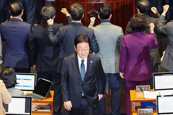 이재명 더불어민주당 대표가 27일 오후 국회 본회의에서 한덕수 대통령권한대행 탄핵소추안 투표를 마친 뒤, 항의하는 국민의힘 의원들 뒤로 미소 지으며 이동하고 있다. ⓒ뉴시스