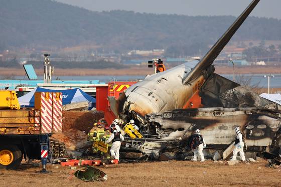Emergency authorities survey the site of a plane crash at Muan International Airport on Dec. 29. [YONHAP]