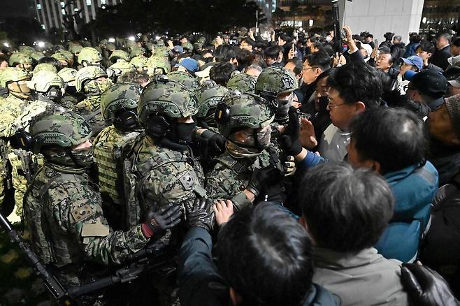 지난 4일 새벽 서울 여의도 국회 의사당에 무장한 계엄군이 진입을 시도하고 있다. AFP 연합뉴스