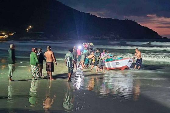 People drag the capsized boat to the shore of Koh Phangan, Thailand, on Sunday. [SCREEN CAPTURE]