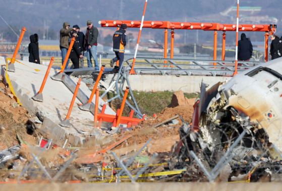 전남 무안군 무안국제공항 제주항공 여객기 참사 현장에서 한·미 합동조사단이 참사 원인으로 지목되고 있는 방위각시설(로컬라이저)에 올라 사고기체를 살피고 있다. 〈사진=연합뉴스〉