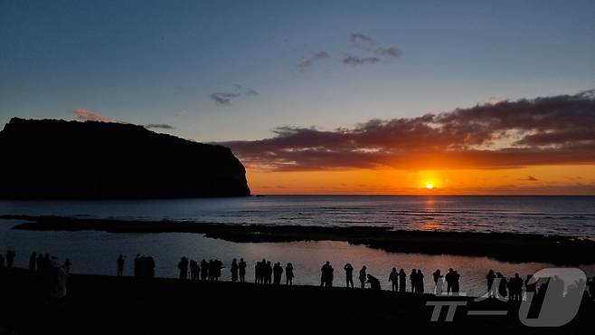 2025년 을사년(乙巳年) 첫날 제주 서귀포시 성산일출봉 인근 해변에서 사람들이 일출을 보며 새해 소망을 빌고 있다.2025.1.1/뉴스1 ⓒ News1 오미란 기자