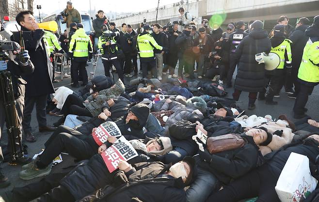 2일 서울 용산구 한남동 대통령 관저 정문 앞 도로에 지지자들이 손팻말을 들고 누워있다. 연합뉴스