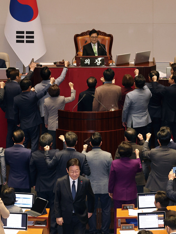 이재명 더불어민주당 대표(맨 앞)가 2024년 12월27일 국회 본회의에서 국민의힘 의원들이 우원식 국회의장에게 항의하는 동안 한덕수 국무총리 탄핵소추안에 투표한 뒤 자리로 향하고 있다. ⓒ연합뉴스