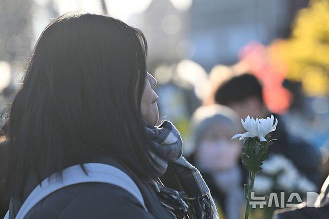 [광주=뉴시스] 이영주 기자 =  2024년 한 해 마지막 날이자 제주항공 여객기 참사 사흘째 되는 날인 31일 오후 광주 동구 5·18민주광장에 마련된 합동분향소에서 한 시민이 국화꽃을 든 채 입술을 깨물고 있다. 2024.12.31. leeyj2578@newsis.com