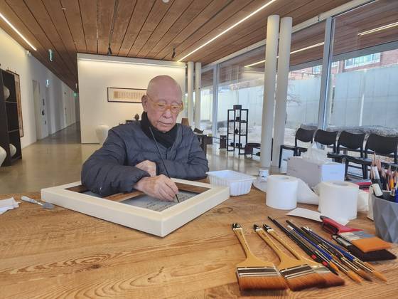 '신문 묘법' 작품 뒤에 서명하는 박서보. 사진 박서보재단