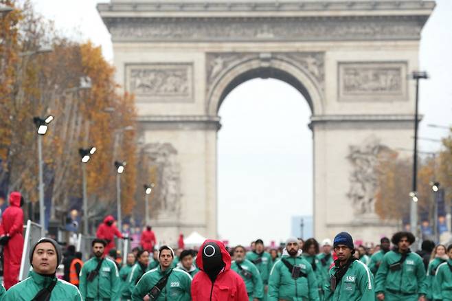 지난해 12월1일(현지시각) 프랑스 파리 샹젤리제 거리에서 넷플릭스 프로그램 '오징어게임'에 기반한 게임에 참가한 사람들과 진행 요원들의 모습/AFPBBNews=뉴스1
